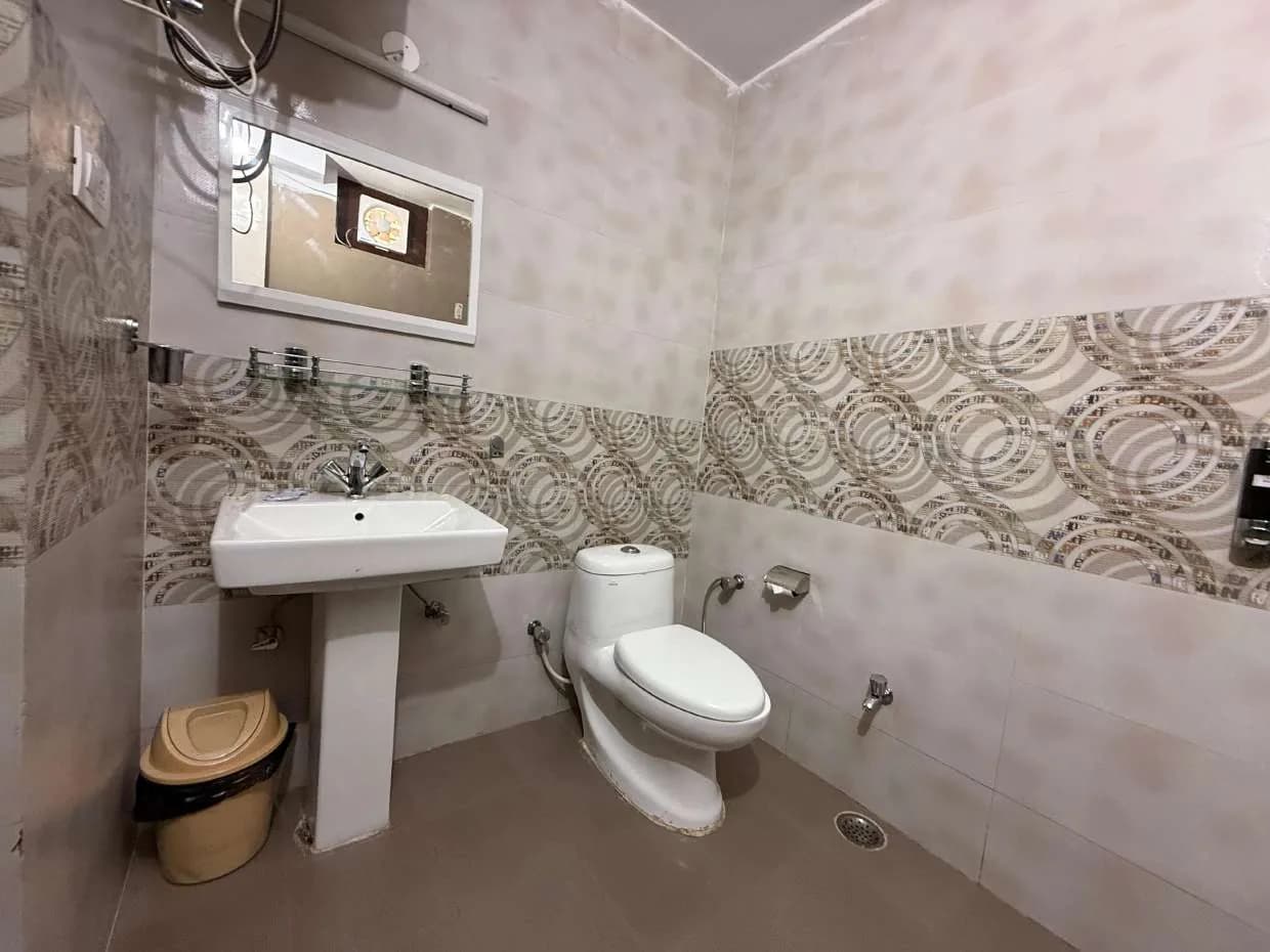 Bathroom with pedestal basin, western toilet and patterned tile band