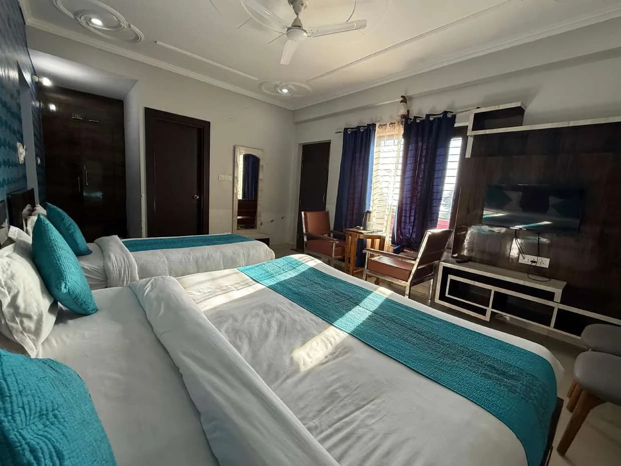 Room with two beds, wall-mounted TV and navy curtains at the window