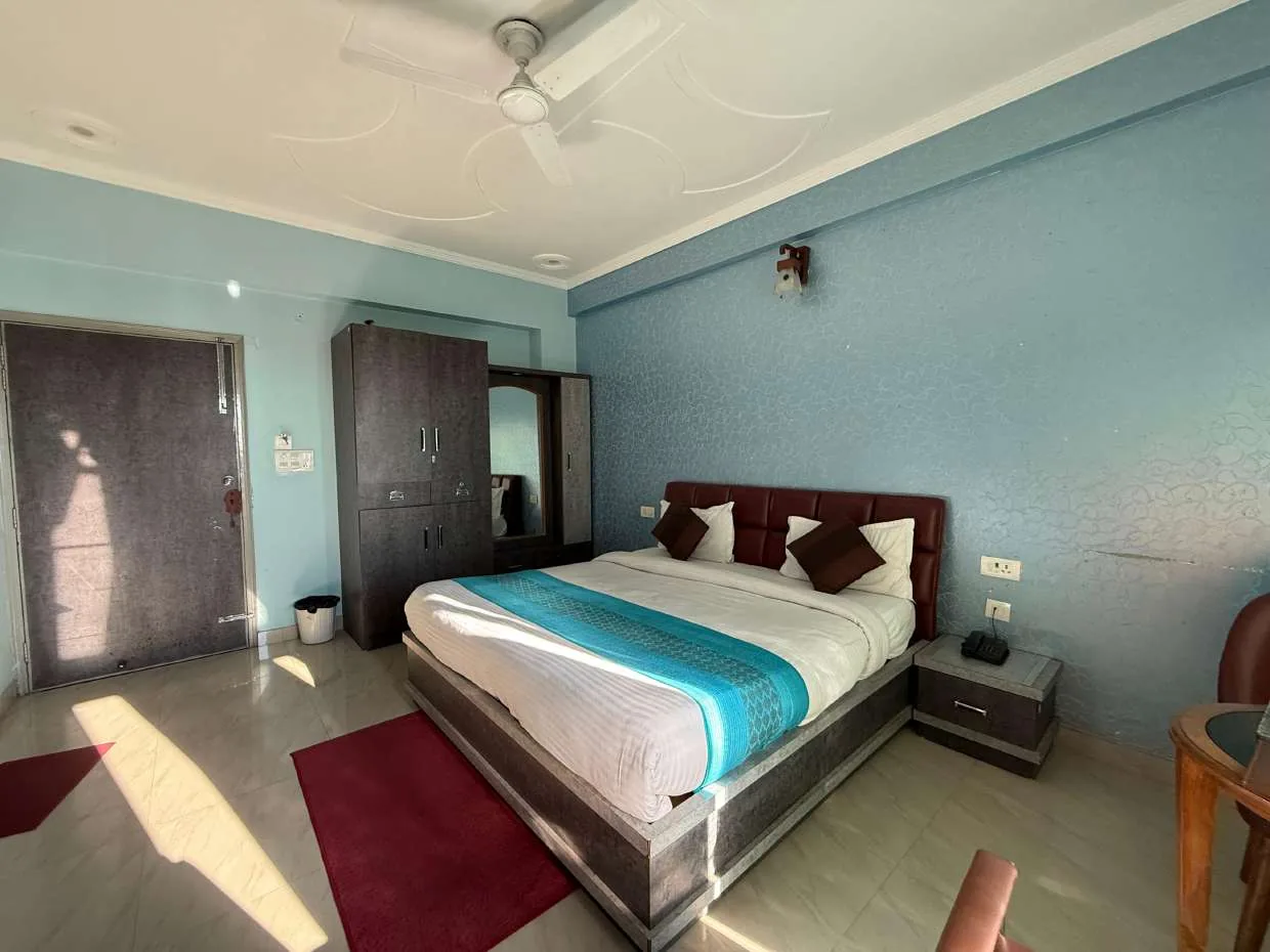 Light-blue room with double bed, wardrobe and entrance door