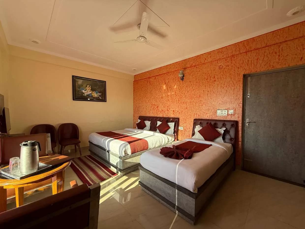 Room with two beds against an orange textured wall and a tea table in the foreground