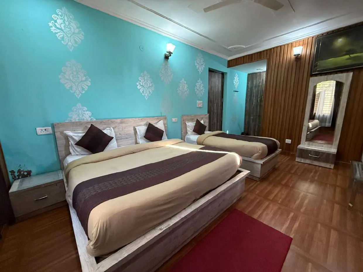 Room with a double bed and a smaller bed against a teal damask wall