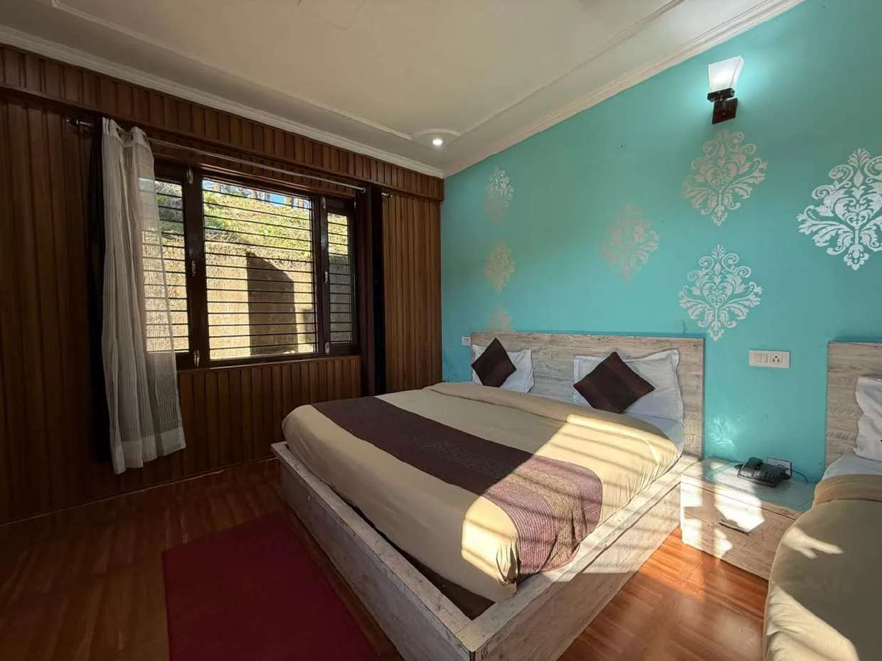 Room with a double bed, teal damask wall and wood-panelled window wall