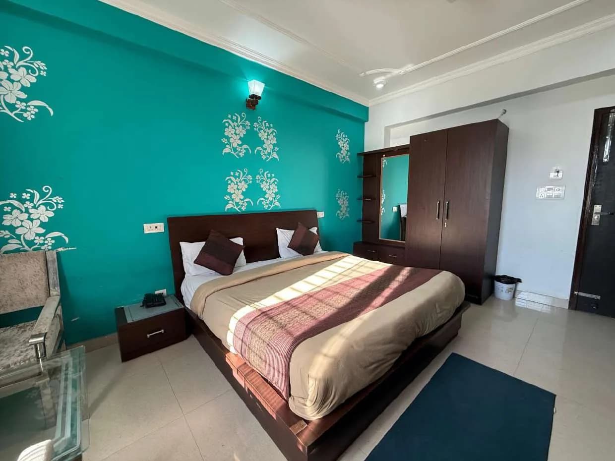 Room with a double bed against a teal wall with white floral stencils